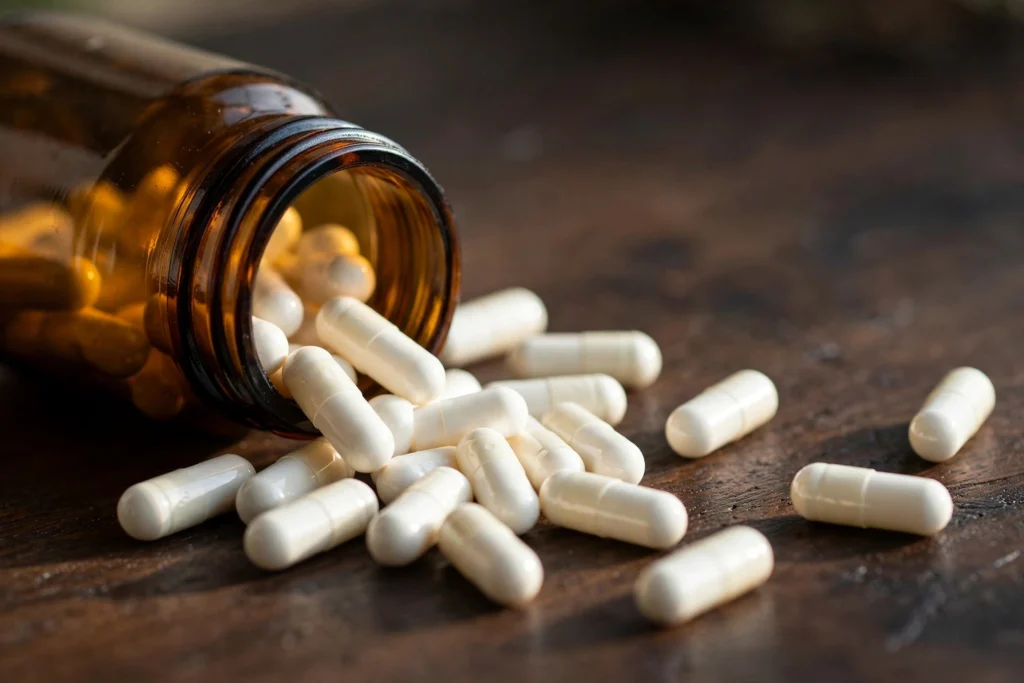 White supplement capsules spilling from an amber pill bottle — Relaxium Sleep review